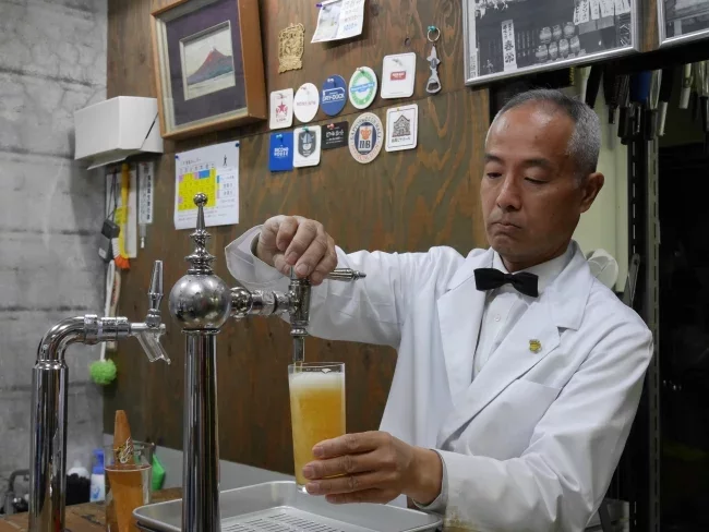 Yutaka Shigetomi sert une bière au comptoir de son établissement à Hiroshima